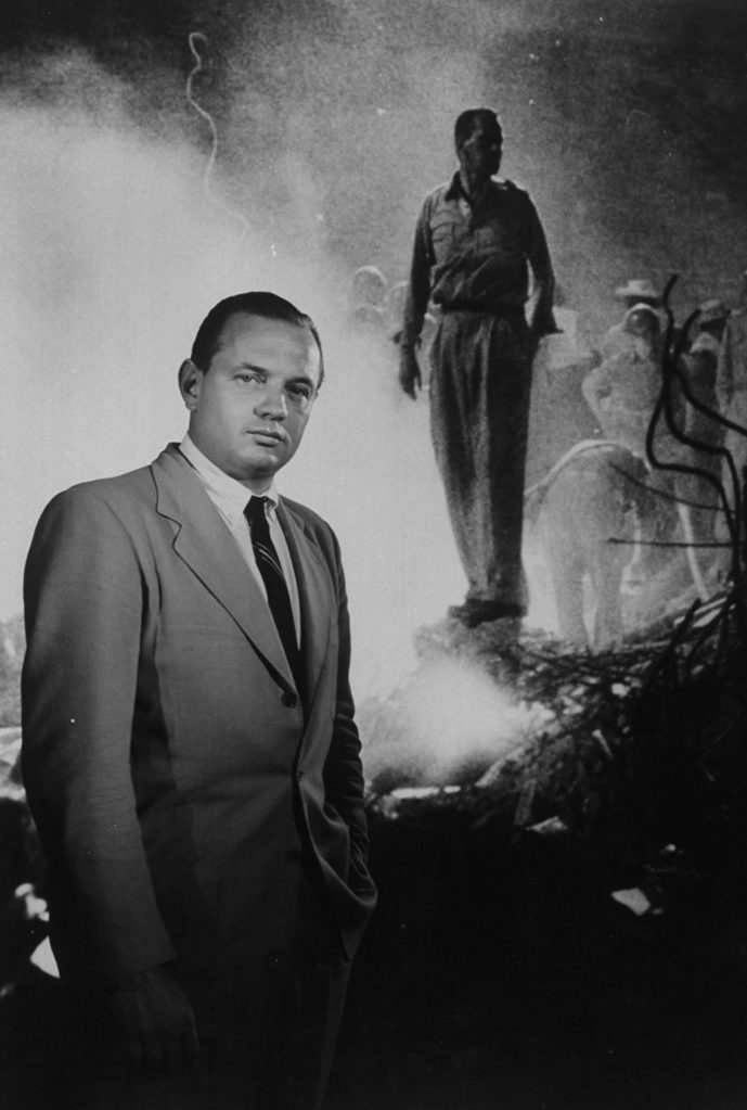 Joe Scherschel posed in front of combat photo he had taken.(Photo by Yale Joel/The LIFE Picture Collection © Meredith Corporation)