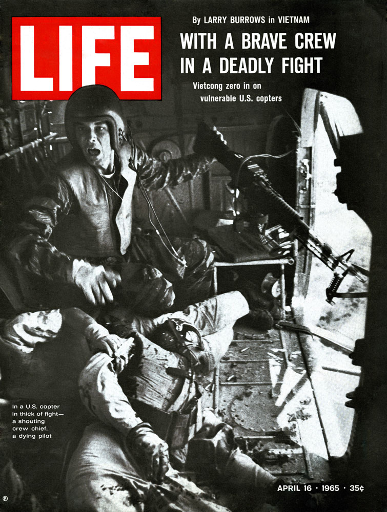 Lance Cpl. James C. Farley, helicopter crew chief, yells to his pilot while in flight after a firefight in Vietnam, 1965.