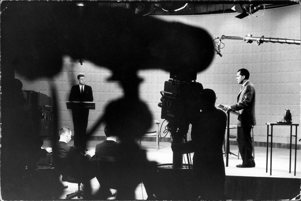 (Left to right) Presidential candidates Sen. John Kennedy and Richard Nixon stand at lecterns as moderator Howard K. Smith presides at first debate, 1960.