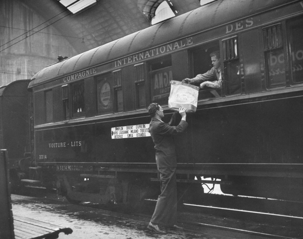 In Milan, [a man] hands a diplomatic packet through window.