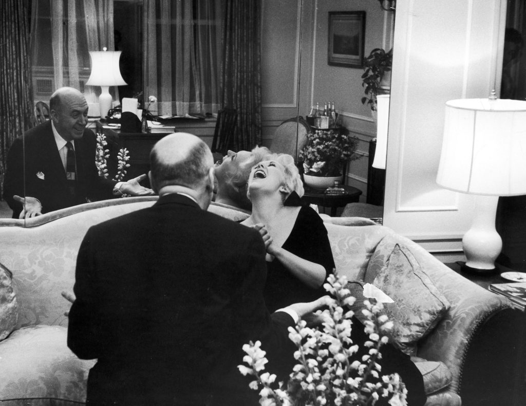 A rare laugh from somber Kim greets joke by Otto Preminger who visits Kim while she is in New York. She has great fondness and respect for Preminger, who directed her in United Artists' Man With the Golden Arm and put her genuinely at ease.