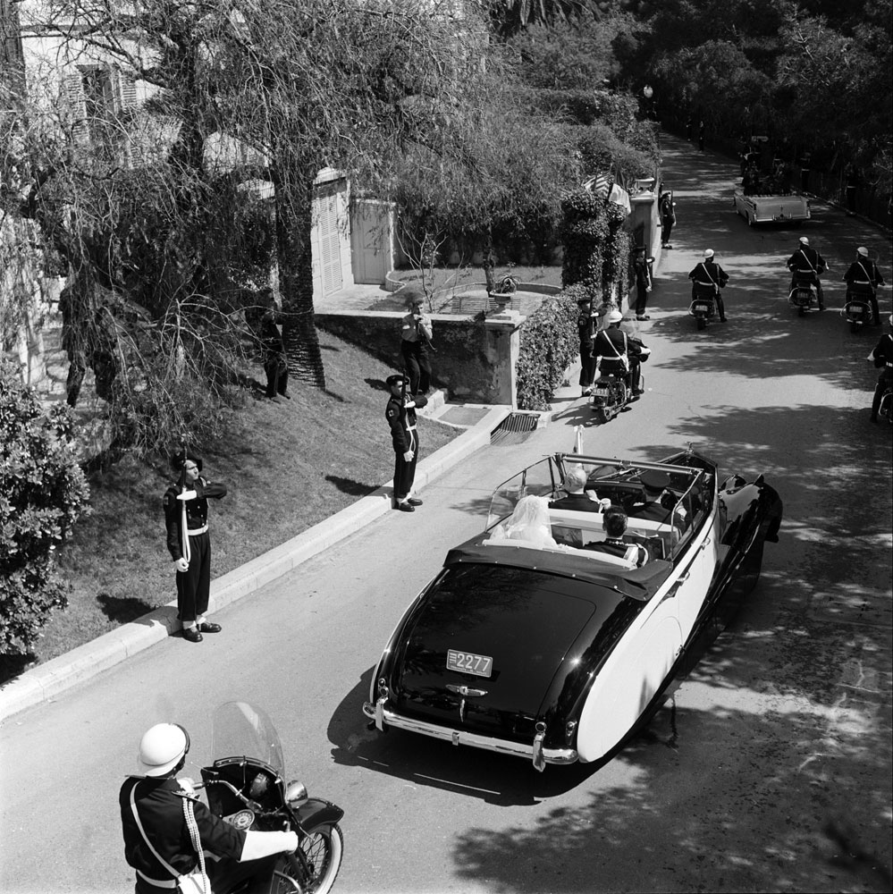 Princess Grace and Prince Rainier III, newlyweds, are whisked away in a Rolls Royce convertible, April 1956.