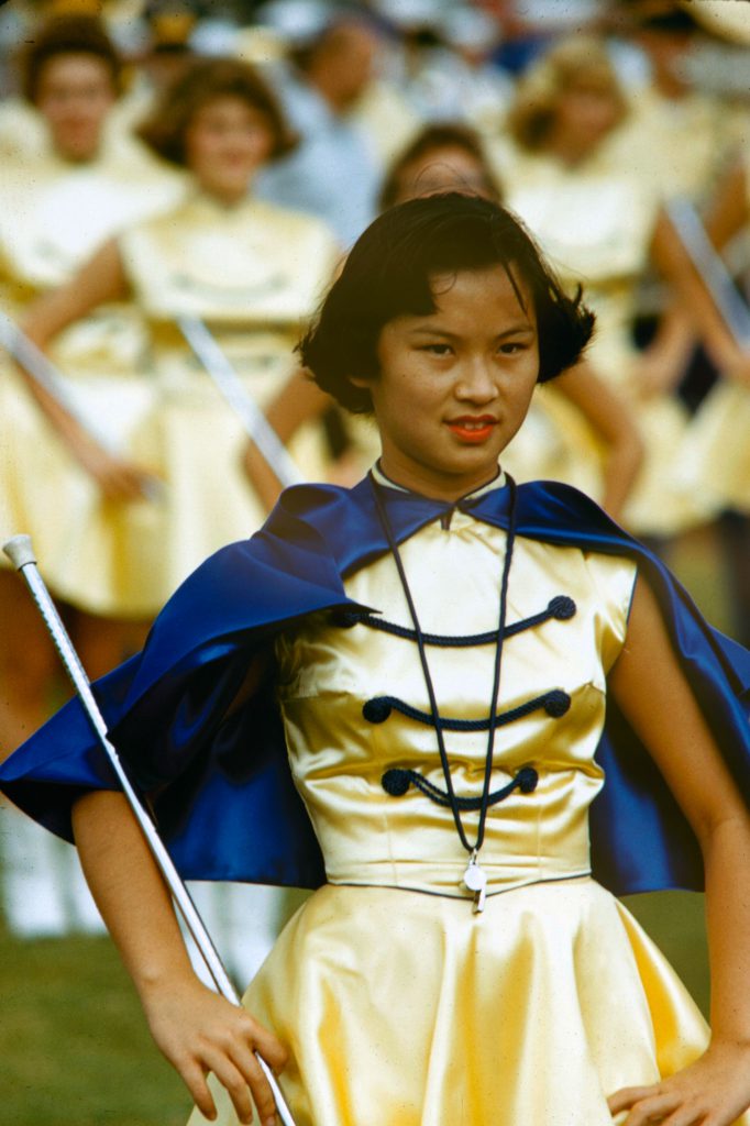 Drum majorette leads band at Honolulu football game, 1959.