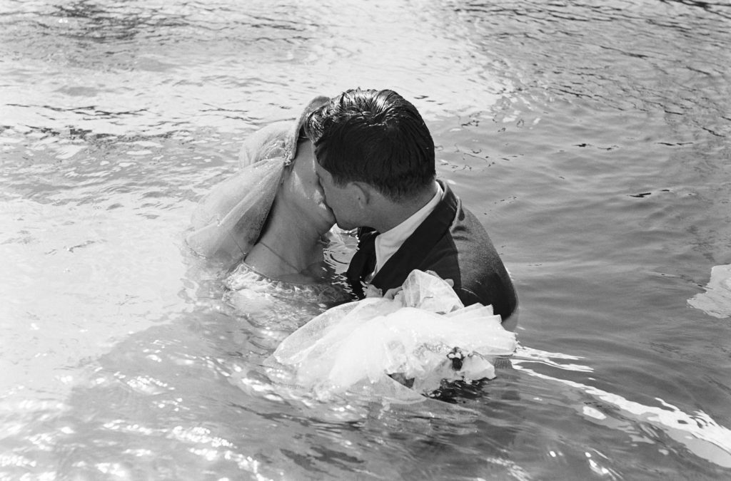 Bride and groom kiss after underwater wedding.