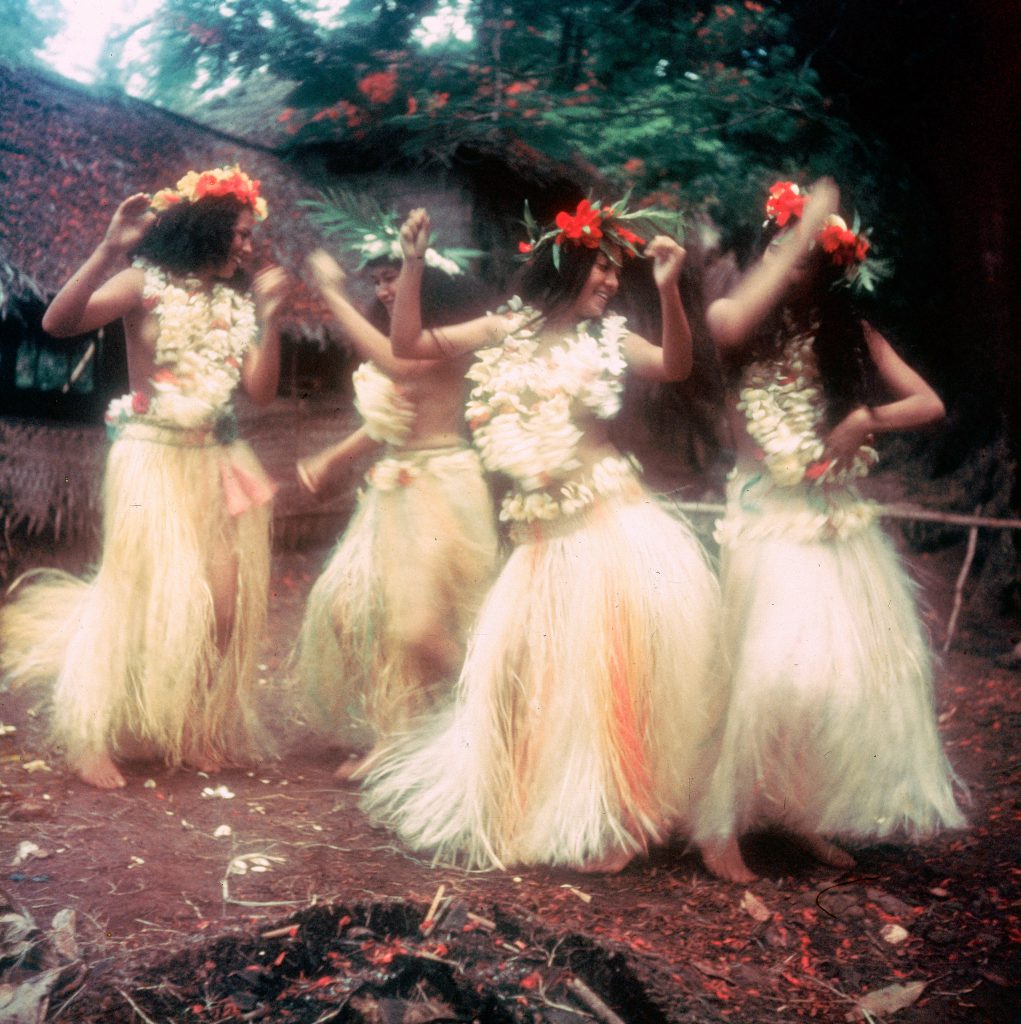 Girls in frangipani blossoms swirling in a frenzied dance.