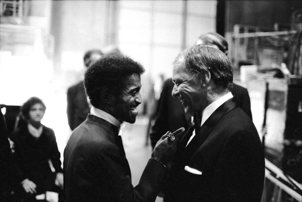 Sammy Davis Jr. talking with singer Frank Sinatra at his farewell peformance, at UCLA, 1971.