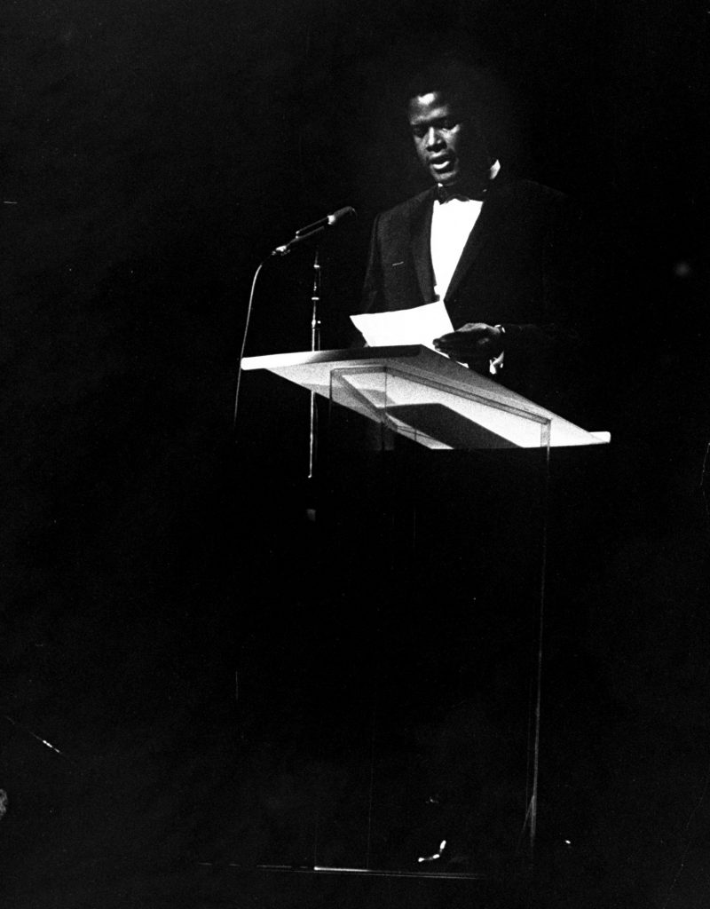 Sidney Poitier speaking at a pre-Inaugural gala for President John F. Kennedy, 1961.