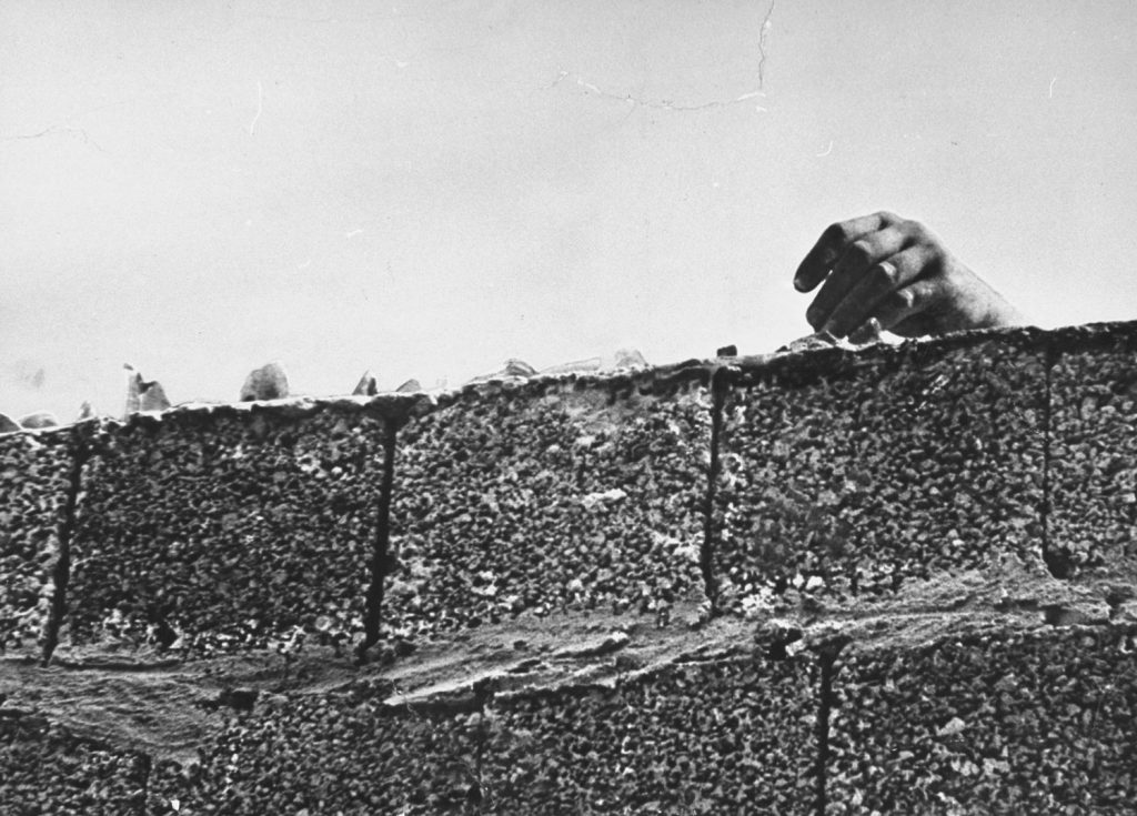 A hand is seen atop the Berlin Wall