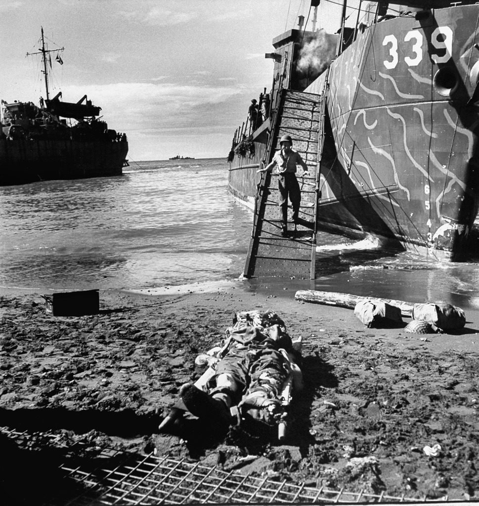 American soldier descending the steps of an LCI towards body of an Australian serviceman killed by a Japanese bomb. (Photo by Myron Davis/The LIFE Picture Collection © Meredith Corporation)