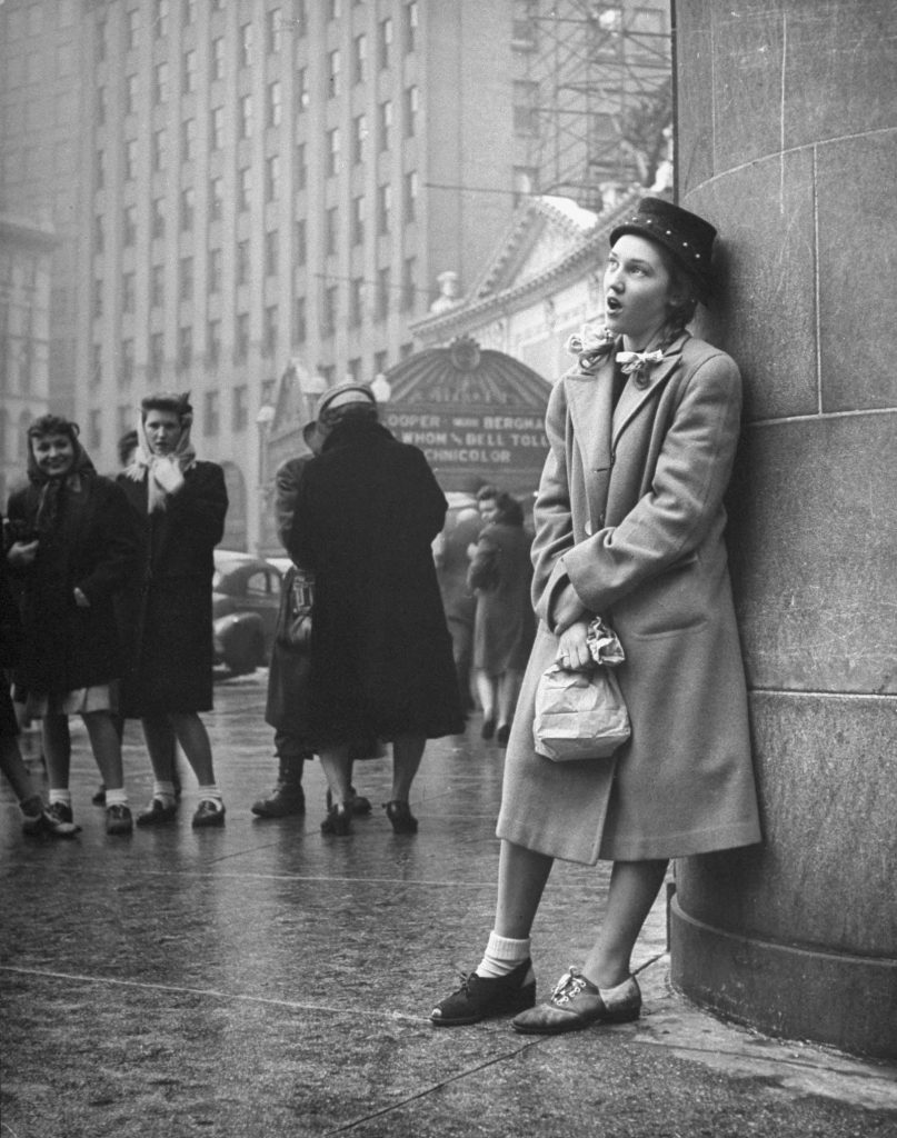 A teenager sings on a street corner as part of a sub-deb social club initiation in 1945.